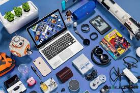 Flat lay of electronic gadgets and accessories including laptop, tablet, smartwatch, and tech devices on blue background.