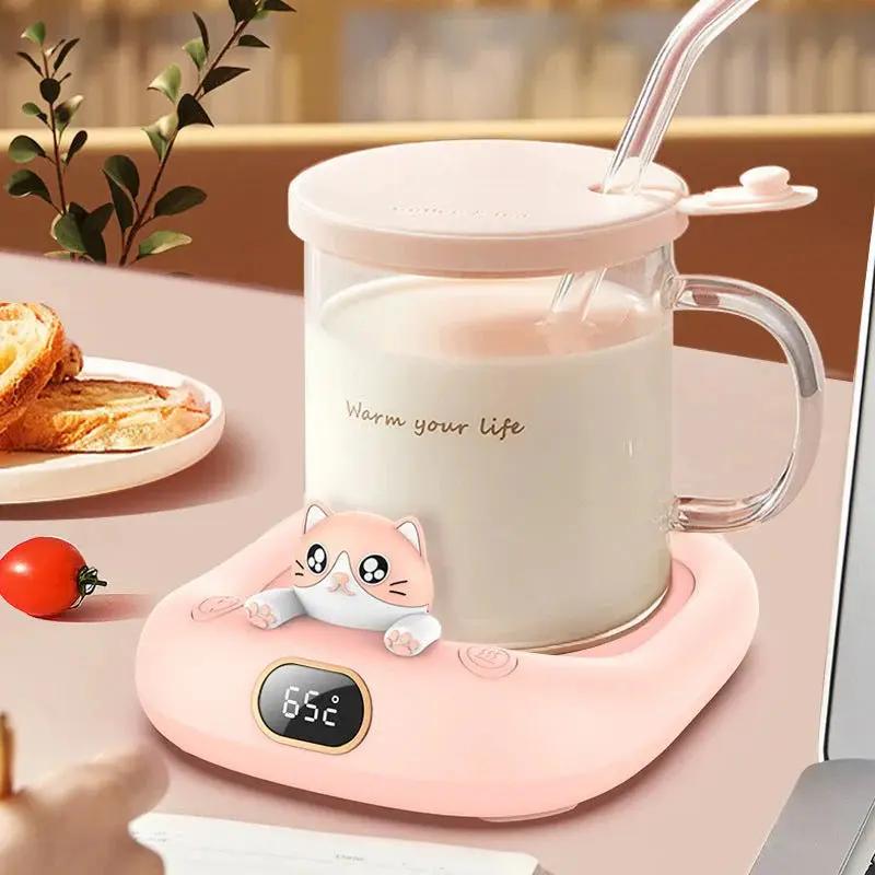 Pink cat-themed mug warmer holding a glass cup on a home office desk, digital temperature display